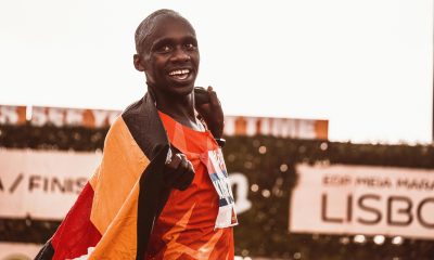 Athlete celebrating victory draped in flag after marathon race.