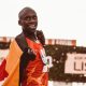 Athlete celebrating victory draped in flag after marathon race.