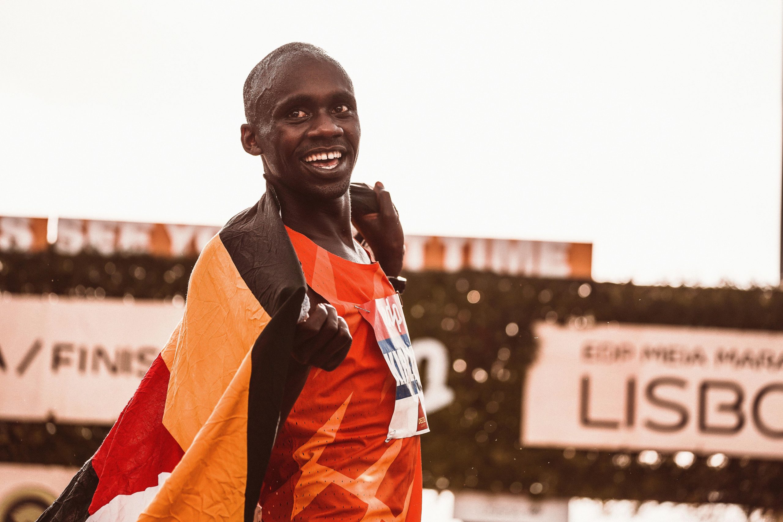 Athlete celebrating victory draped in flag after marathon race.