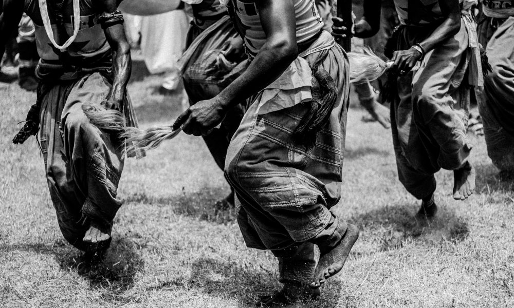 Black and white photo of a traditional dance ceremony outdoors in Ilorin, Nigeria.