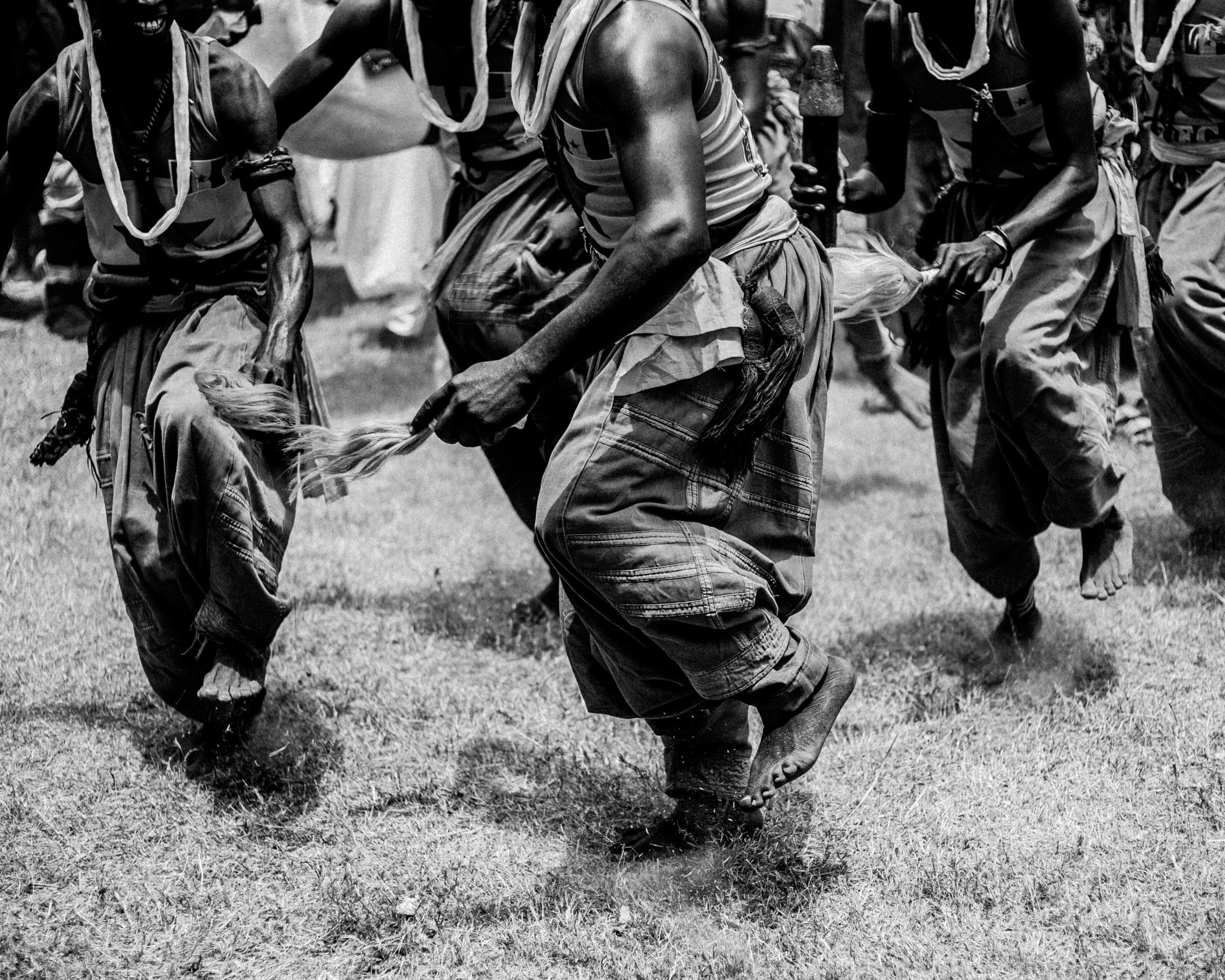 Black and white photo of a traditional dance ceremony outdoors in Ilorin, Nigeria.