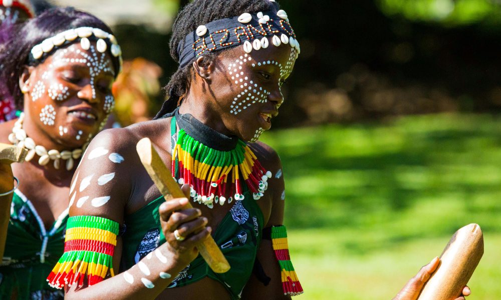 Two women in traditional attire perform a vibrant dance outdoors in The Gambia.