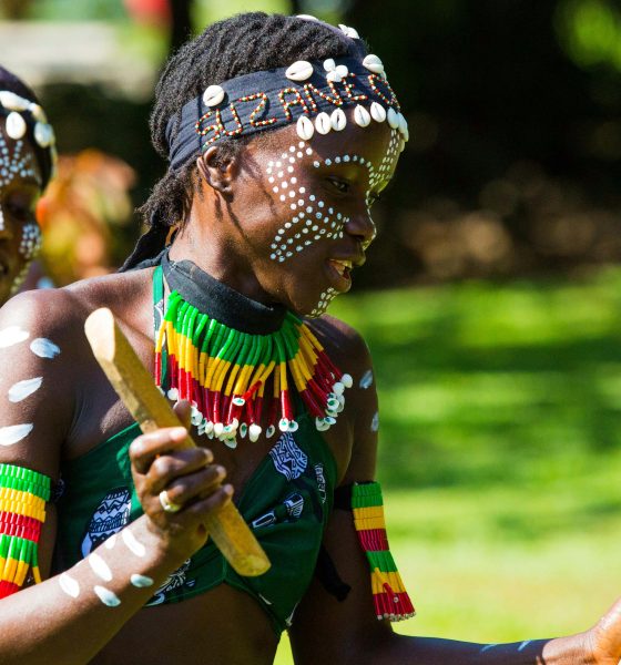 Two women in traditional attire perform a vibrant dance outdoors in The Gambia.