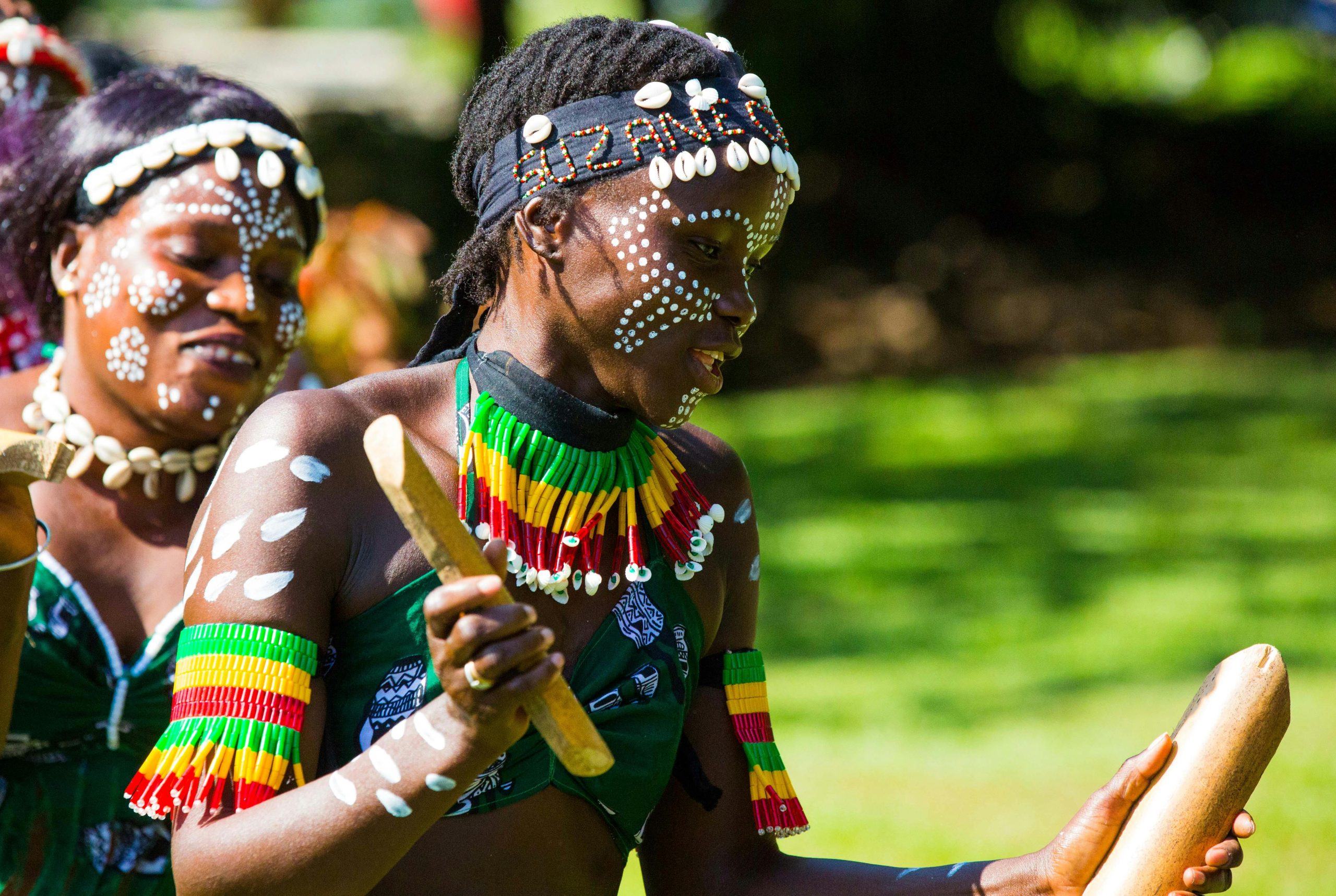 Two women in traditional attire perform a vibrant dance outdoors in The Gambia.