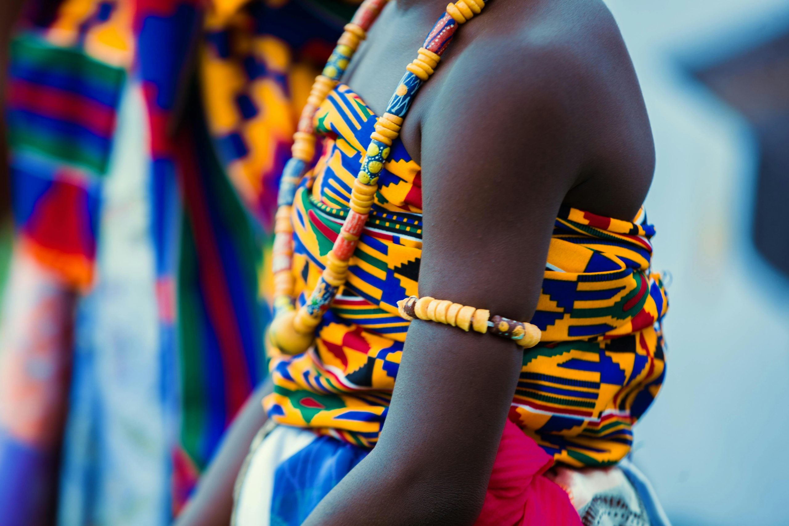 Vibrant traditional Ghanaian attire with beads and kente cloth, highlighting cultural identity.