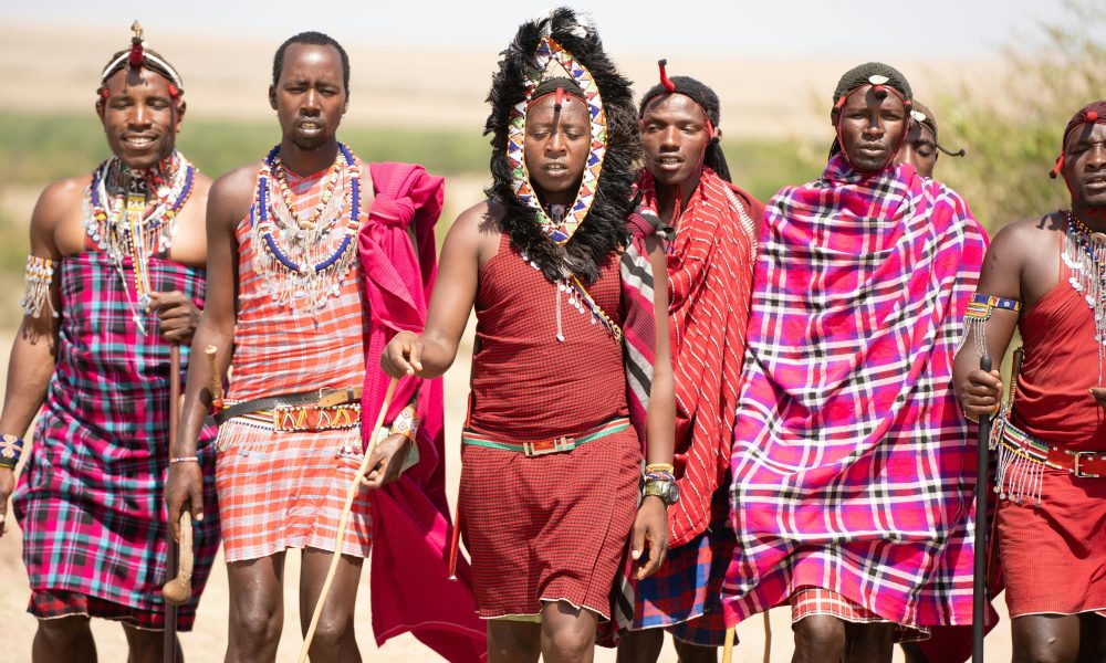 Group of Maasai men in traditional attire walking in the Kenyan landscape.