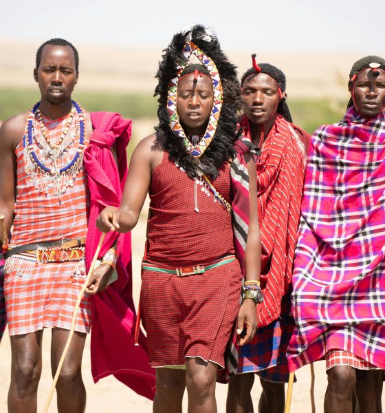 Group of Maasai men in traditional attire walking in the Kenyan landscape.