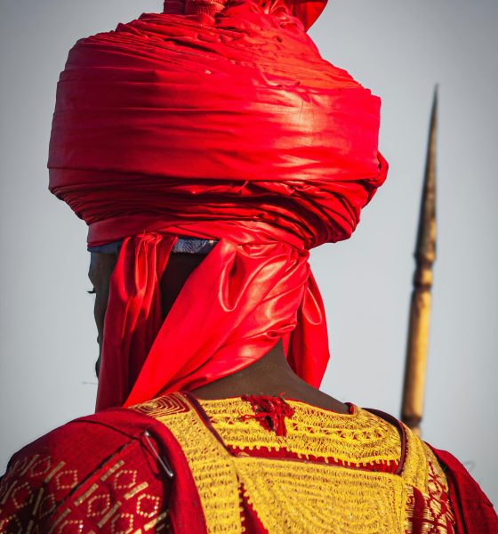 Man in traditional African attire with a striking red turban, symbolizing cultural heritage.