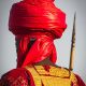 Man in traditional African attire with a striking red turban, symbolizing cultural heritage.