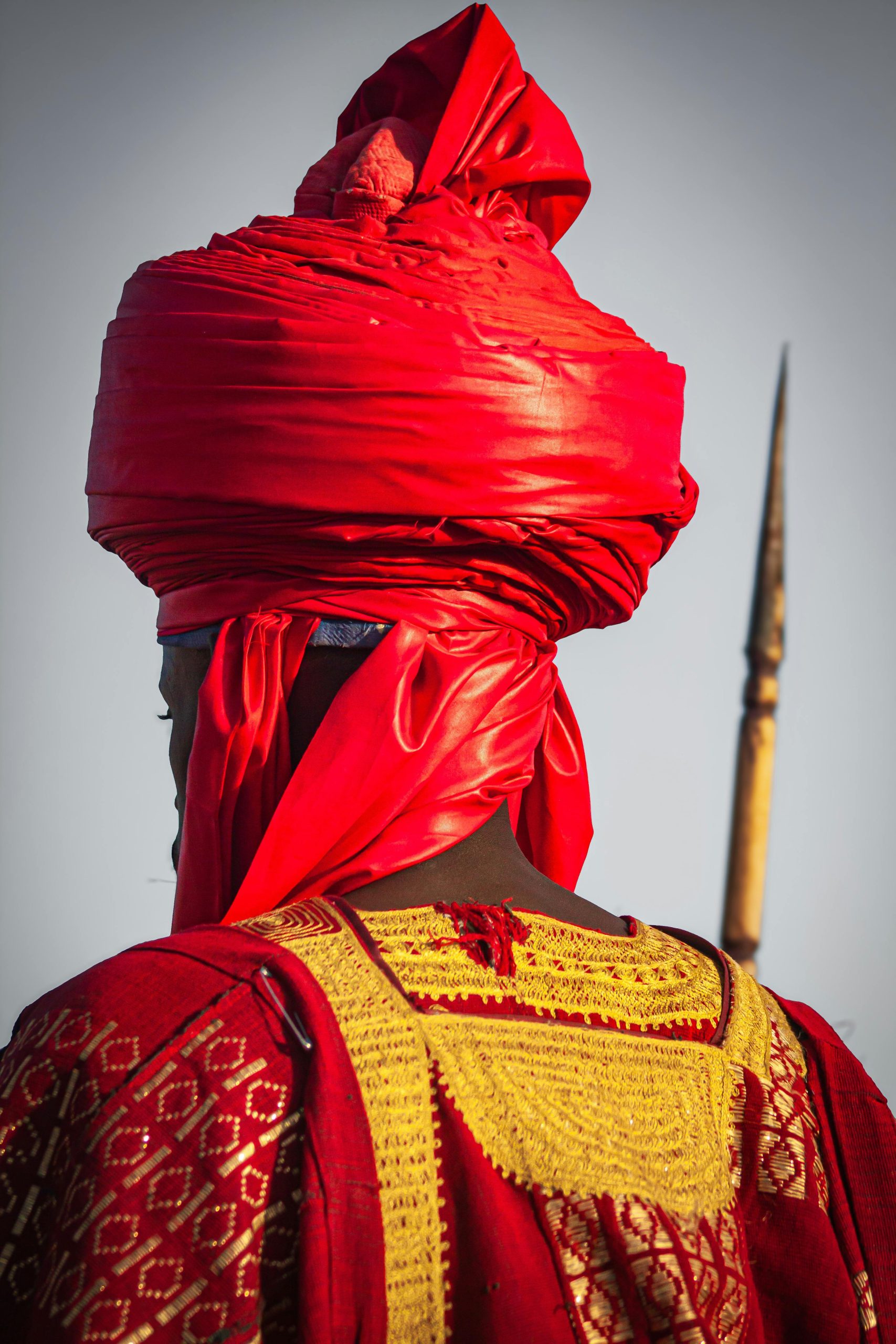 Man in traditional African attire with a striking red turban, symbolizing cultural heritage.
