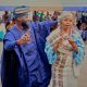 Vibrant celebration with African couple in colorful traditional outfits dancing joyfully outdoors.
