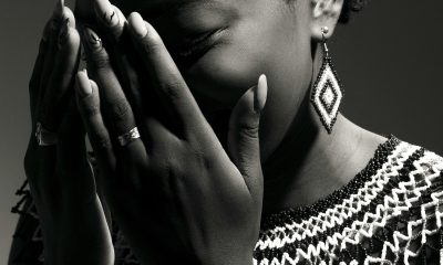 A stunning black and white portrait of a woman wearing traditional jewelry, covering her face with her hands.