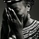 A stunning black and white portrait of a woman wearing traditional jewelry, covering her face with her hands.