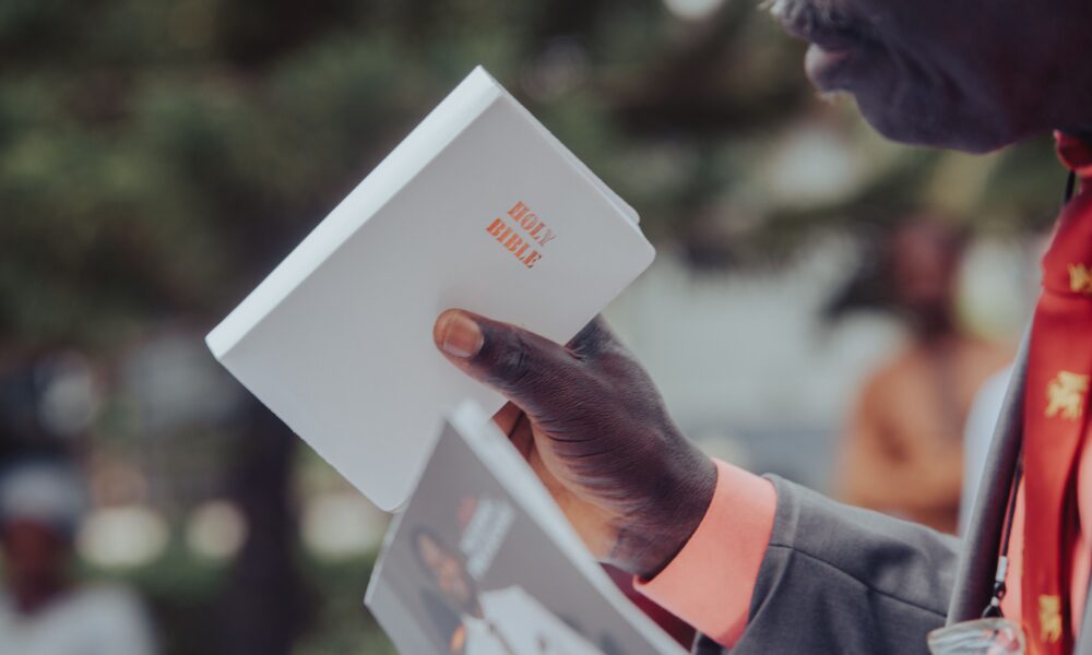 Adult man holding a Holy Bible, participating in an outdoor event, Ibadan, Nigeria.