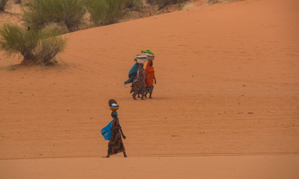 Captivating scene of women in traditional attire traversing the sandy desert in Yusufari, Nigeria.