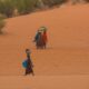 Captivating scene of women in traditional attire traversing the sandy desert in Yusufari, Nigeria.